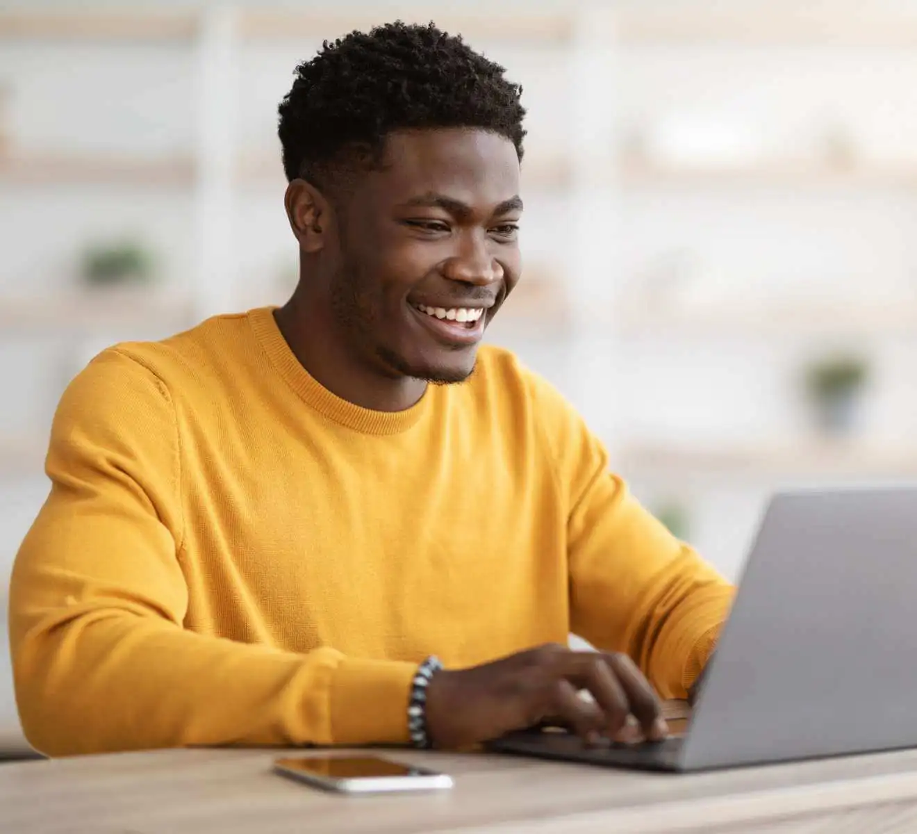 A man is smiling while using a computer