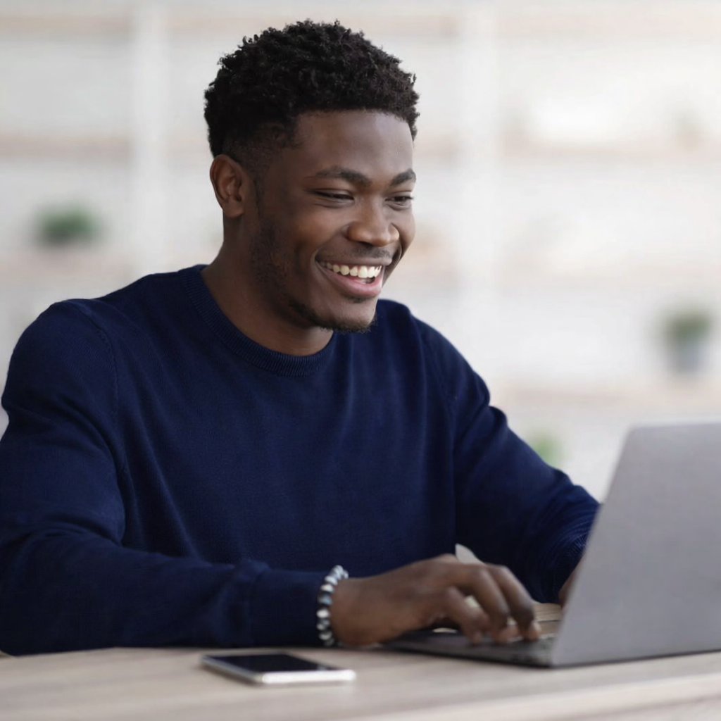 A man is smiling while using a computer