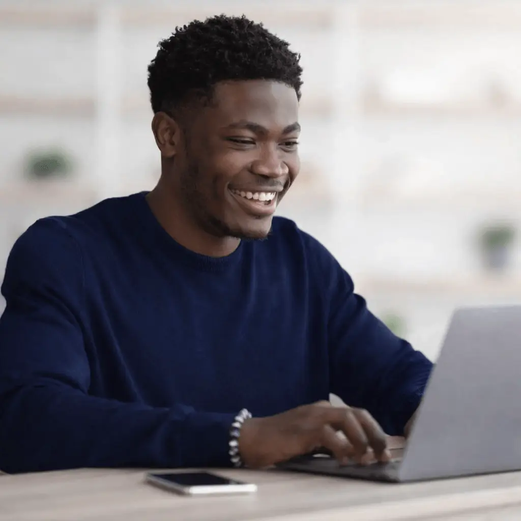 A man is smiling while using a computer